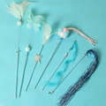 Set de 6 varitas de juguete para gatos con plumas, cascabeles y cinta azul sobre fondo azul - Juego de 6 Varitas para Gato Azul
