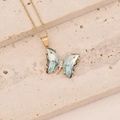 Détail d'un collier papillon doré orné de pierres bleu clair et de zircons blancs - Rose bonbon