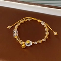 Detail of yellow citrine bead bracelet with golden lotus charm on dark leather tray - Citrine White Crystal Beaded Bracelet