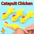 Elastic yellow turkey slingshot toy being stretched by fingers for launching action - Catapult Turkey