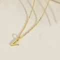 Elegant gold letter V pendant necklace on a textured cream minimalist background - Letter V(VXL2998)