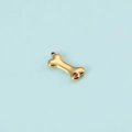 Detailed view of a gold bone pendant featuring a vibrant red zircon stone on blue background - Gold January