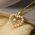 Dettaglio macro del ciondolo a cuore dorato con perle e scritta LOVE scintillante - Perla LOVE Lettera Cuore