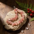 Macro detail of natural pink crystal moon hair clip on a rustic stone background - Strawberry Quartz