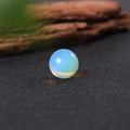16mm light blue opal sphere gemstone with orange shimmer on a dark textured surface - Opalite