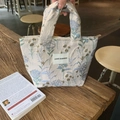 Detail van bloemig borduurwerk op witte stoffen tas met geweven handvat en rits - Jacquard Bladeren