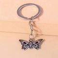 Detail shot of gothic butterfly keychain with skull wings and coffin-shaped body - Cross Coffin Butterfly
