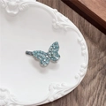 Detail of silver butterfly hair clip with light blue rhinestones on a ceramic plate - Single Butterfly / Green