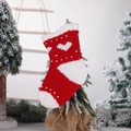 Rote und weiße Strick-Weihnachtssocke mit Herzmuster an festlichen Tannenzweigen - Herz-Stil Gestrickte Socke