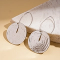 Macro view of silver geometric earrings with concentric circle texture and metallic finish - Silver