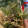 Close-up of golden acrylic Happy New Year Christmas tree topper with festive pine cones - HAPPY NEW YEAR / Golden Christmas Tree