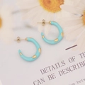 Chic light blue enamel C-shaped earrings with gold teardrop accents on floral background - Blue