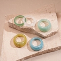 Close-up of colorful resin acrylic rings with marble texture on stone display - Blue Set