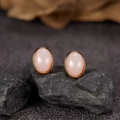 Close-up of S925 silver oval pink jade stud earrings on a dark textured stone base - Natural Pink Opal Oval Gold 5*7mm