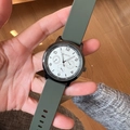 Macro shot of an olive green silicone watch band and black casing held by hand - Dark Green