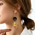 Gothic gold spider earrings featuring a black faceted bead on a model ear - Black Gold (Black Gold S554)