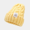 Detail of chunky cable knit yellow beanie showing clear texture and fabric patch label - Yellow