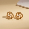 Close-up of golden spiral flower earrings with a pearl center on a textured background - White Pearl / Gold
