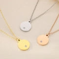 Dettaglio di collane in oro, argento e oro rosa con pendenti rotondi su tessuto seta - Stile Disco Tondo / Color Acciaio