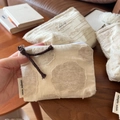 Detail of beige cotton linen pouch with 3D floral texture and zipper pull strap - Rosebud Coin Purse