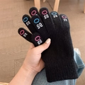 Close-up detail of black knit touchscreen gloves featuring cute embroidered eye patterns on fingers. - Black