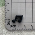 Close-up of mini black resin music note showing 1.2cm size on a measuring ruler - Black