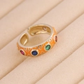 Makrodetail eines orangefarbenen Goldrings mit bunten Zirkoniasteinen auf Samt - Einstellbar Offen / Orange