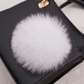 Gros plan d'un accessoire pompon en fourrure naturelle blanche sur un sac en cuir - Style Bouton Pression 14CM / Blanc