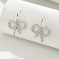 Silver bow knot earrings with zircon stones displayed on a minimalist white stand - Silver Openwork Ear Hook Style (EH4586-9)