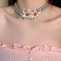 Bohemian layered pearl necklace with dual white flowers and vintage red beads on a model - Double Layer Pearl Red Bead Flower Necklace (DX0795)