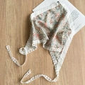 Close-up of floral print head scarf with elegant white lace borders on a wooden surface - Orange