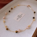 Dettaglio della collana lunga con perle occhio di tigre in scatola portagioie crema - Oro