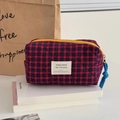 Vintage red and blue plaid quilted cosmetic bag with yellow zipper on book - Red