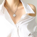 Collar de moneda reina plateada con cadena asimétrica sobre modelo con camisa blanca - Color acero