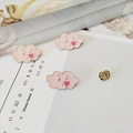 Close-up of pink cloud enamel brooch with heart detail and butterfly clasp on fabric - Cloud