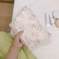 Dettaglio della borsa trucco floreale con etichetta semplice e vari cosmetici - Ciliegio Rosa