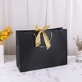 Elegant black paper gift bag featuring a golden ribbon bow and matching rope handles - 28*9*20cm / Black