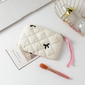 Close-up of white quilted cosmetic bag with black bows and pink woven zipper pull - Beige Fabric with Embroidered Bow