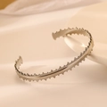 Detail shot of silver stainless steel bangle featuring unique jagged edge texture design - Silver Sawtooth