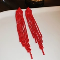 Nahaufnahme der roten Strass-Quastenohrringe auf einem Keramiktablett mit Glanz - Rot (Pfeil)