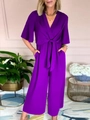 Dettaglio di una tuta viola con scollo a V, gamba larga e fiocco in vita alla moda - S / Viola