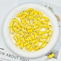 Macro shot of yellow fish-shaped ceramic beads for DIY jewelry making in a white bowl - Yellow