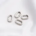 Detail van vier gepolijste zilveren ovale veerringen voor doe-het-zelf sieraden op witte stof - Platina Kleur Ovalen Veerring 16x9.5mm