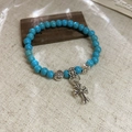 Close-up of vintage stone bead bracelet with turquoise color and silver cross pendant - Small / Blue