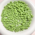 Macro view of 6mm green cylindrical acrylic beads for handmade jewelry in a white bowl - Fruit Green