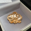 Gedetailleerde weergave van orchideeënbroche in gepolijst goud op grijze fluwelen doos - Goud