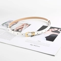 Cintura da donna in pelle bianca con fibbia dorata a H esposta su rivista di moda - Bianco