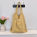 Dettaglio borsa shopper a quadri gialli appesa con decorazioni floreali in ambiente accogliente - Giallo a Quadri