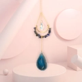 Close-up of agate slice and crystal crescent moon suncatcher on pink geometric stands - Blue Sodalite