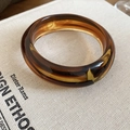 Detailed texture of amber resin bangle showing marbled tortoiseshell pattern on book - Coffee Closed Oval Style